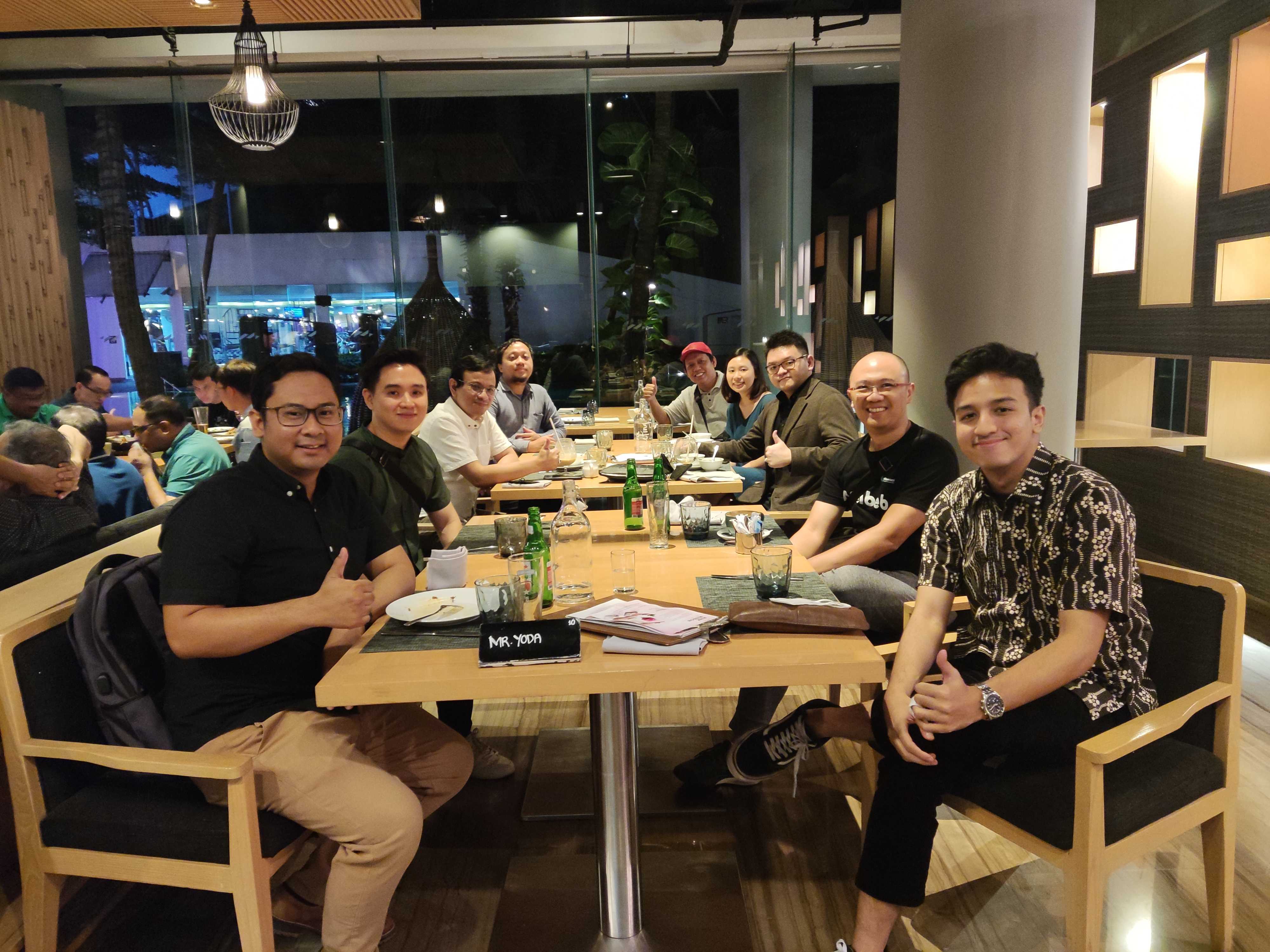 A group of people at dinner facing the camera and smiling in Jakarata, Indonesia