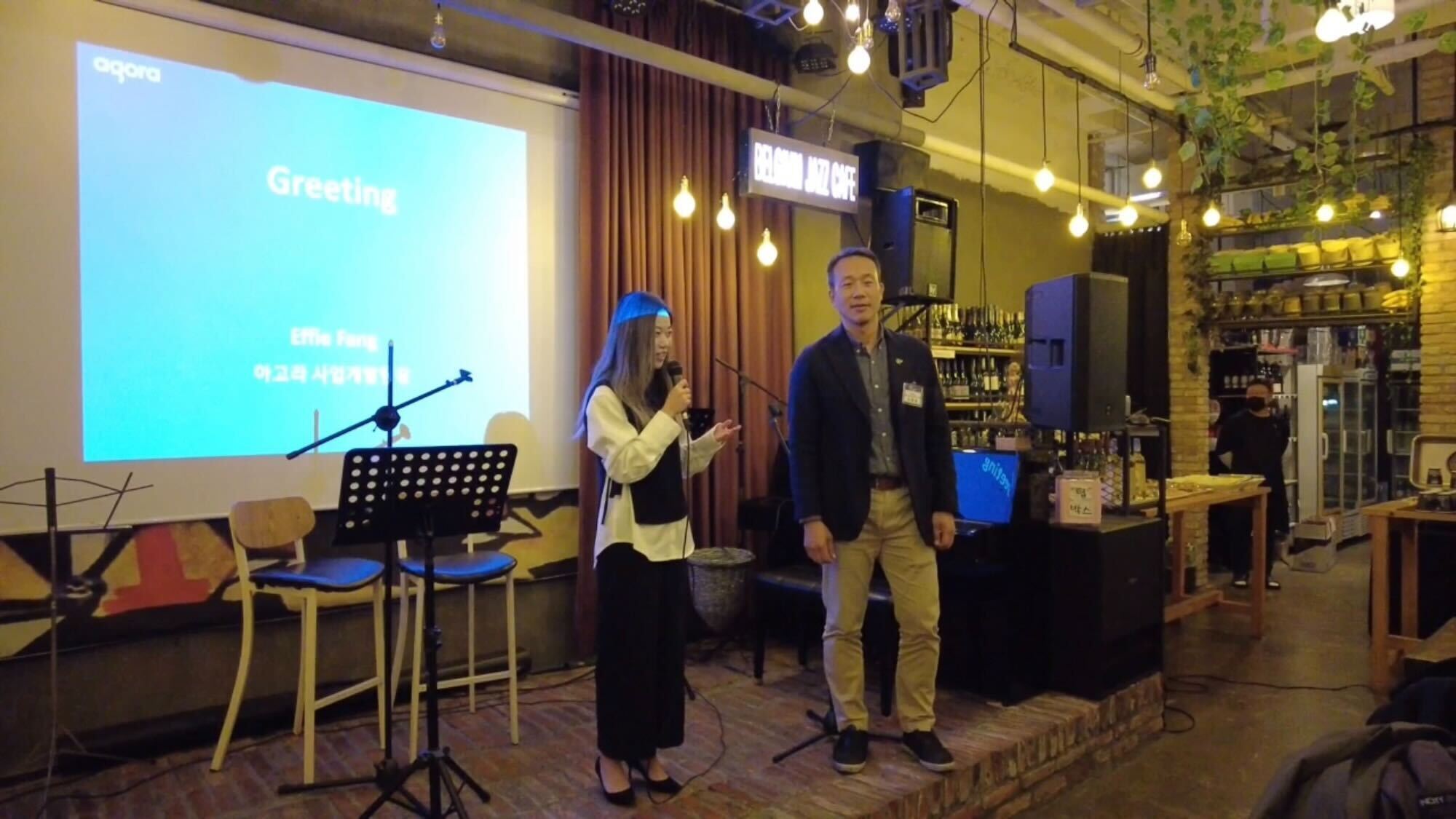 Two people presenting on a stage in Seoul, South Korea