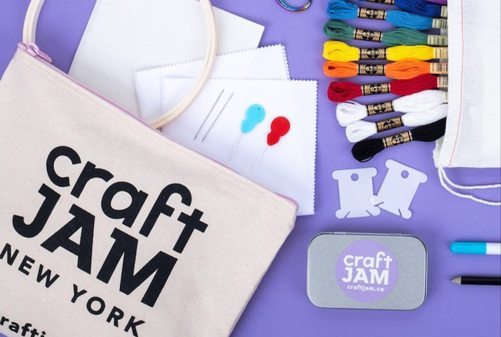 Bag with CraftJam logo and craft supplies on purple table