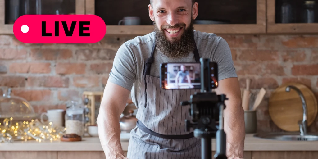 A man in an apron cooking on a live video call