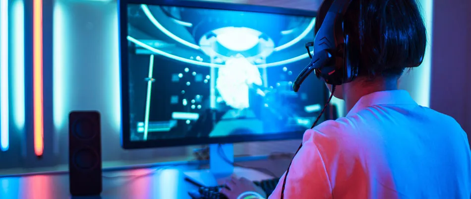 A female playing game on a computer with headsets